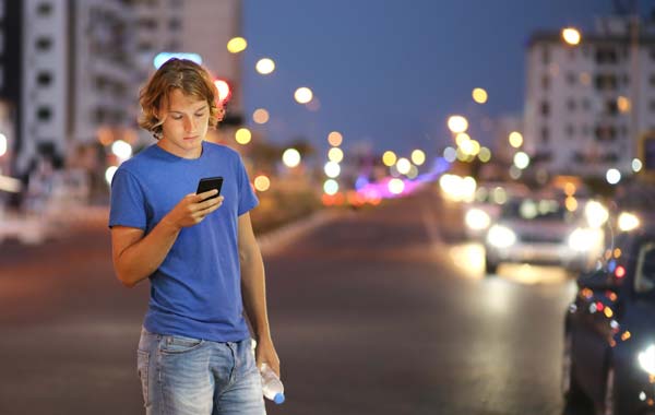 Man using smartphone while crossing the road